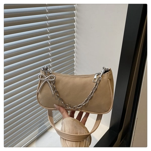 Détail du sac en cuir beige avec chaîne argentée et pendentif noeud élégant