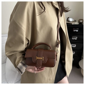 Detail of dark brown vintage crossbody bag with gold buckle and adjustable strap