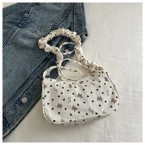 Detail of white corduroy underarm bag with bow print and ruffled shoulder strap