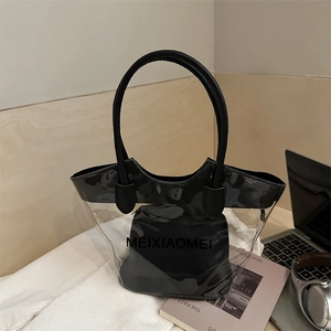 Transparent PVC tote bag with black leather inner pouch in a cozy lifestyle setting