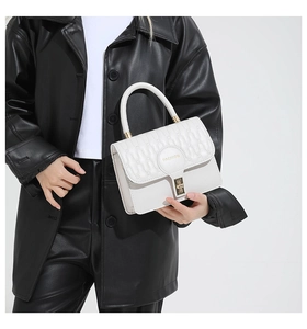 Close-up of white wavy quilted handbag with gold clasp and 'FASHION' embossed detail