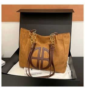 Detail view of brown suede tote bag in gift box with chain handle and round logo