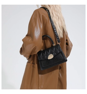 Detail view of black crocodile pattern crossbody bag with gold lock and quilted flap