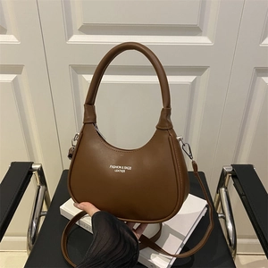 Brown half-moon crossbody bag with gold lettering on a stylish leather surface