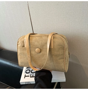 Close-up of a large khaki suede tote bag held against a chic Tom Ford inspired backdrop