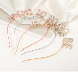 Close-up of Mom To Be metal headbands in gold, silver and rose gold with rhinestones