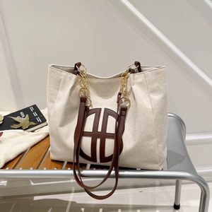 Minimalist beige suede tote bag with brown circular pattern and gold chain shoulder strap