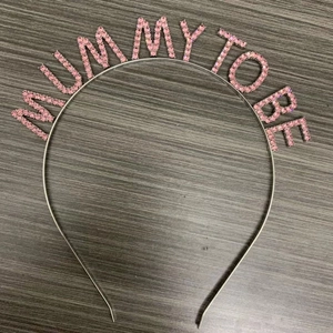 Close-up of Mommy To Be headband with pink rhinestones for baby shower party