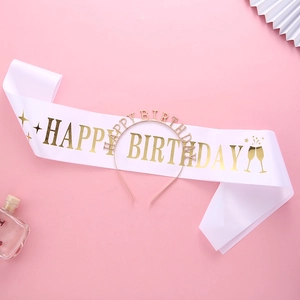 Gros plan sur l'écharpe d'anniversaire en satin blanc et le diadème doré Happy Birthday