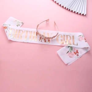 Detail of rose gold crystal tiara and white Birthday Girl sash with floral patterns