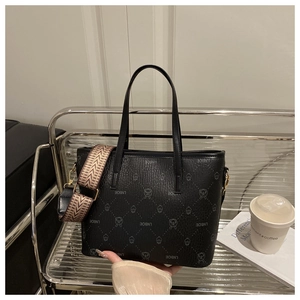 Detailed view of black bucket bag with LNBOE monogram and woven strap on a display shelf