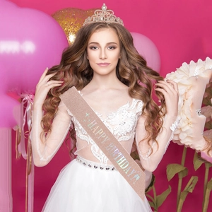 Detail of rose gold birthday sash and crystal crown worn by a model in party setting