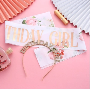 Detail of rose gold birthday girl headband and floral sash on pink background