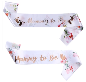 Detalle de la banda de satén blanco con motivos florales y texto dorado Mommy to Be