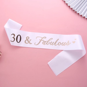 Détail de l'écharpe en satin blanc avec lettrage rose doré 30 & Fabulous et cœur