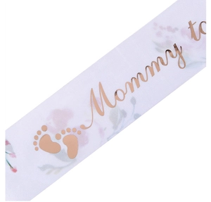 Detalle de la banda Mommy to be en satén blanco con letras en oro rosa y flores