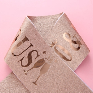 Gros plan d'une écharpe pailletée or rose avec lettres métalliques et motifs de fête