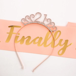 Macro shot of rose gold 21st birthday rhinestone tiara and pink satin ceremonial sash
