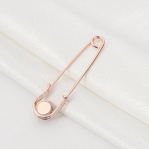 Macro detail of rose gold safety pin brooch on elegant white silk textured background