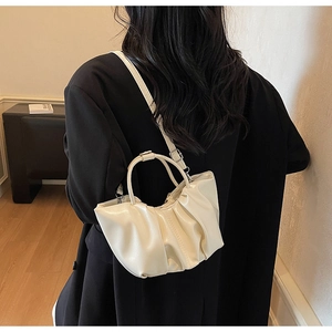 Detail of a creamy beige pleated cloud handbag with silver hardware and thin shoulder strap