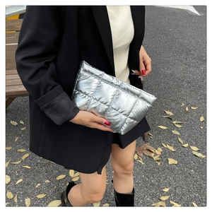 Street style view of a silver quilted clutch bag with metallic finish and chic checkered stitching