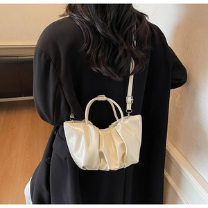 Detail of off-white pleated cloud bag showing glossy leather texture and adjustable strap