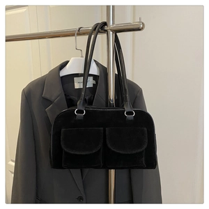 Détail d'un sac à main vintage en daim noir avec double poches sur un support argenté