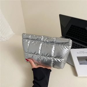 Chic silver metallic quilted clutch bag with padded texture in a modern office setting