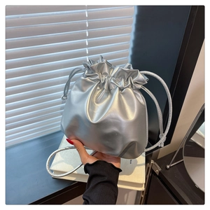 Detail of a shiny silver drawstring bucket bag with a soft metallic leather texture