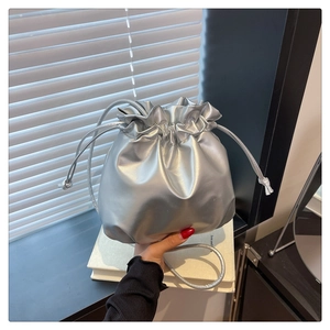 Detailed view of silver drawstring bucket bag with metallic texture and sleek shoulder strap
