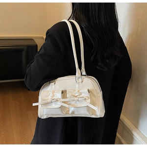 Detail view of white patent leather shoulder bag with decorative bows on the side pockets
