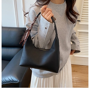 Detail der schwarzen Hobo-Tasche aus Leder mit elegantem Seidenschal am Handgriff