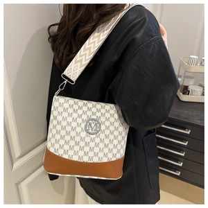 Detail of adjustable wide woven strap and monogram print on the beige bucket bag