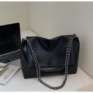 Detail of black wrinkled leather tote with silver chain and subtle logo print