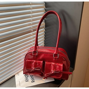 Detailed view of red patent leather handbag with dual pockets and delicate ribbon bows