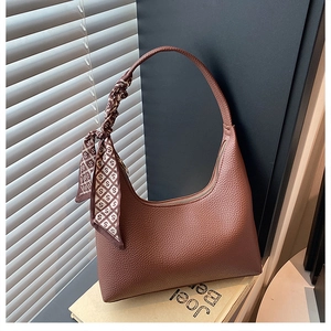 Detail der dunkelbraunen Lederhandtasche mit Lychee-Muster und bedrucktem Seidenschal