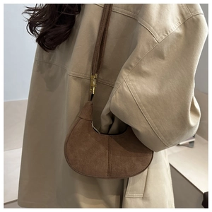 Detail of a brown suede crescent bag featuring vintage matte texture and gold metal buckles