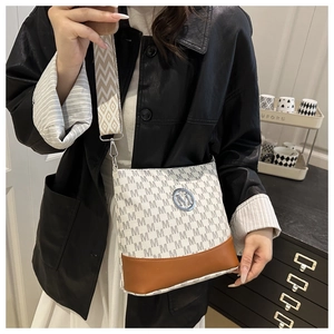 Detail of crossbody bucket bag with letter patterns and round metal logo on wide strap