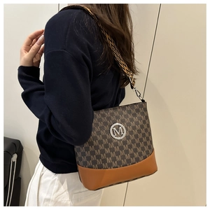 Detailed side view of brown patterned bucket bag with retro geometric woven shoulder strap