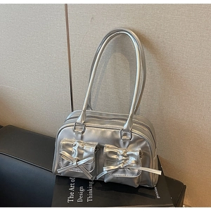 Detail of metallic silver bowling bag featuring dual handles and bow-decorated front pockets