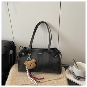 Détail du sac cabas vintage en cuir noir avec étiquette FASHION et breloque ours