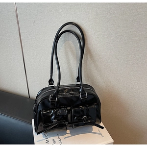 Detail of black patent leather shoulder bag with decorative bows and silver hardware