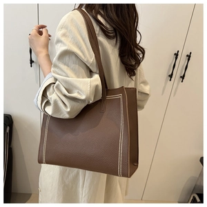 Dettaglio della borsa tote in pelle marrone con motivo litchi e cuciture a pois bianchi