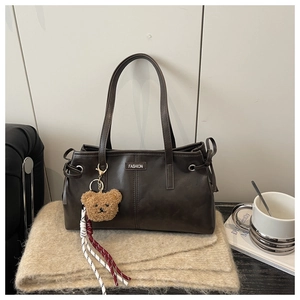 Détail du sac cabas marron foncé en similicuir avec charme d'ours et logo métal