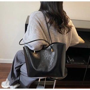 Detail of black oil-wax leather tote bag with gold hardware and minimalist thin straps