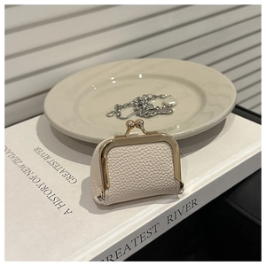 Detalle de un mini monedero de cuero crema con cierre de clip dorado estilo vintage