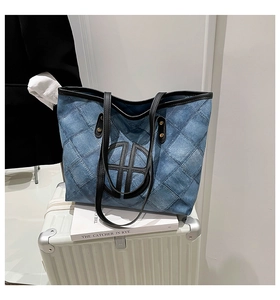 Detail shot of checkered denim tote bag featuring a round logo on a white suitcase