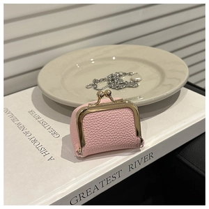 Mini estuche de joyería rosa con cierre de clip en cuero sobre un fondo de libro