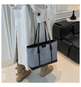 Detail of dark grey textured tote bag with black leather trim and long shoulder straps