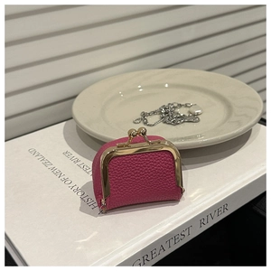Detalle de un mini monedero de cuero rojo rosa con cierre de clip dorado estilo vintage
